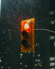 Red stoplight glowing in the pouring rain at night
