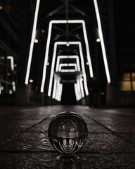 Clear glass ball on the ground reflects the glowing frames of a tunnel corridor at night