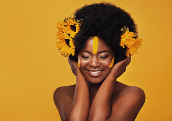Beautiful woman, sunflowers in hair and make up on face in studio for cosmetics, afro care and...
