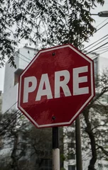 Fotobehang Vertical shot of the Spanish word "Pare" sign with the background of tree. Translation: Stop © Wirestock