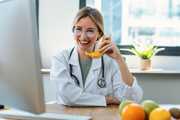 Beautiful young woman nutritionist playing with a banana as if it were a telephone on a nutritionist consultation