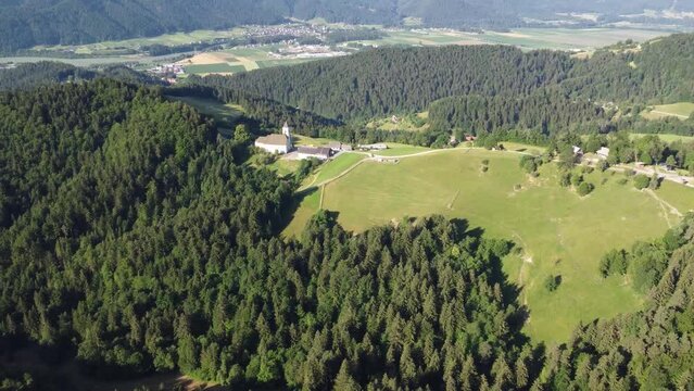 Drone shot over green forested hills and meadows under sunny blue sky