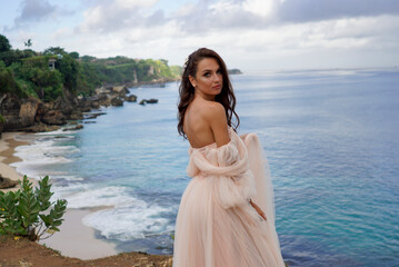 The bride stands gracefully on the cliff's edge