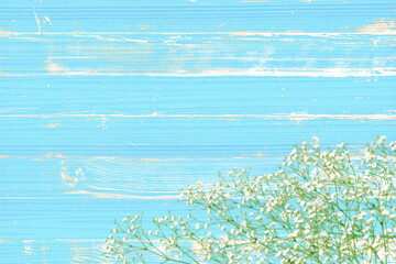シャビー塗装の青いウッドデッキと、かすみ草の背景
