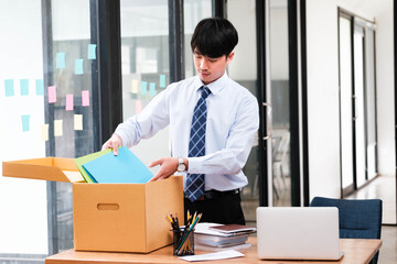 A man in a suit is opening a cardboard box on a desk