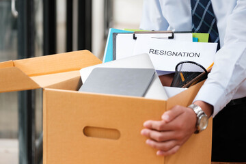 Man places personal items and resignation letter into a box, ending his tenure. - obrazy, fototapety, plakaty
