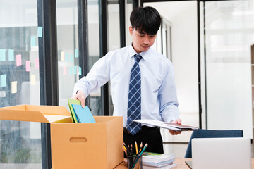 A man in a suit is opening a cardboard box on a desk
