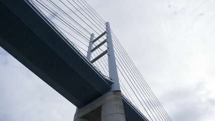 Low angle view of massive suspension bridge against the moody sky