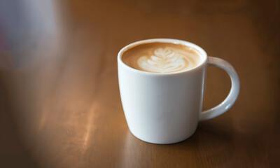 Hot latte art coffee cup on wooden table