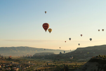 Colorful hot air balloons flying over the landscape of the Red Valley, Rose Valley, close to Goreme, Cavusin, Cappadocia, Turkey