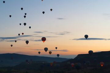 Many hot air balloons rising over the landscape of the Red Valley, Rose Valley before sunrise,...