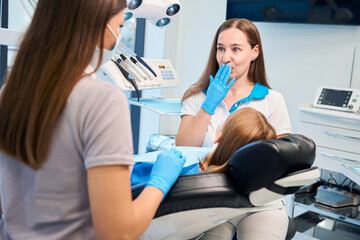 Young dentist and assistant are conducting appointment in dental office