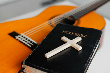 Acoustic guitar with the Holy Bible on the table close up. Worship God.