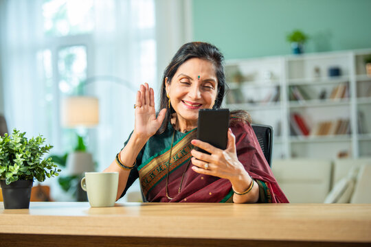Old Indian asian woman using smartphone at home.