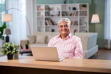 Indian asian senior man using laptop computer at home