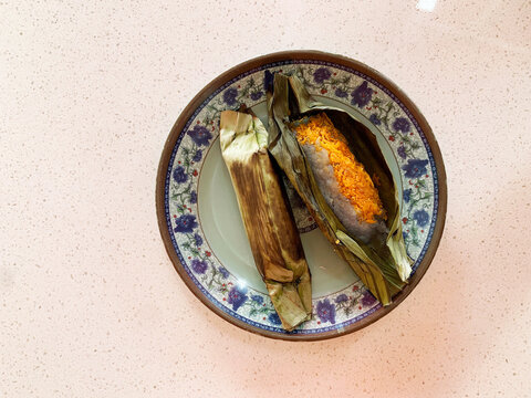 traditional peranakan grilled baked nonya kuih pulut serunding spicy shrimp coconut paste wrapped in banana leaf in plate on vintage table asian cafe hotel luxury halal food restaurant banquet menu
