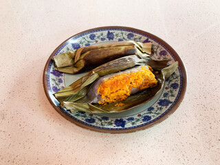 traditional peranakan grilled baked nonya kuih pulut serunding spicy shrimp coconut paste wrapped in banana leaf in plate on vintage table asian cafe hotel luxury halal food restaurant banquet menu