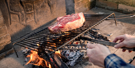 Closeup of a beautiful italian roasted steak on a barbeque grill. Appetizing piece of meat cooking on fire and embers in the backyard. Bbq, recreation, picnic, spring, summer, outdoors cook concept.