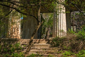 staircase in front of the entrance to a dilapidated temple with a colonnade on a sunny spring day