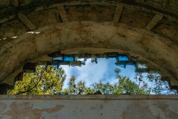 ruins of an abandoned villa in the Greek style - view of the sky through an arch with the remains of glazing under the roof arch on a sunny day