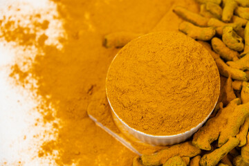 Turmeric powder, spices and dried root on white background.