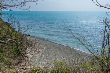 deserted pebble beach of the Black Sea near the mountainside in early spring on a sunny day in April