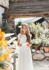 Young girl in white dress with paper, symbolizing purity and faith in a garden setting