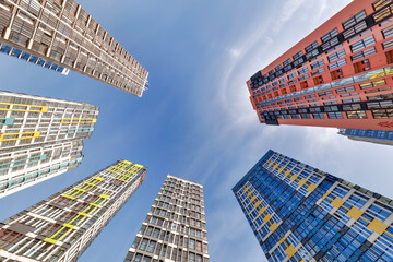 view from below into blue sky with clouds of large modern skyscraper residential complex