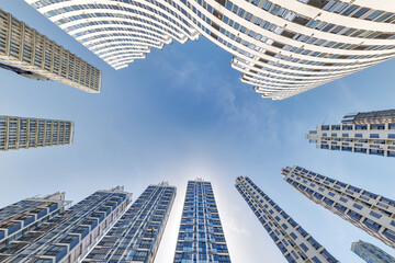 view from below into blue sky with clouds of large modern skyscraper residential complex - obrazy, fototapety, plakaty