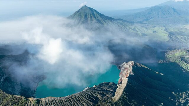 Aerial hyper lapse revealing smoking active Ijen volcano and caldera with surrounding landscape during sunrise on East-Java, Indonesia