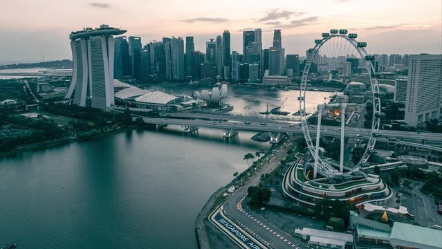 Aerial time lapse of sunset at the Marina Bay area in Singapore turning to blue hour with illuminated city lights