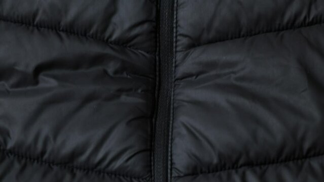 Black puffy winter jacket and zipper as a background close up, black background