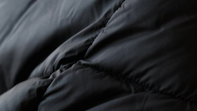 Black puffy winter jacket as a close-up background, black background