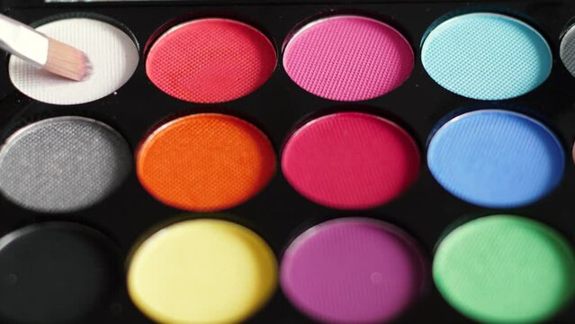 close-up face painting palette with different colors. using a brush to paint the makeup on the face. box with makeup paints and brush