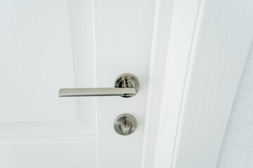 Shiny Metal Door Handle On White Door, Handle Set With Lock, Interior Trim Hardware In Room.