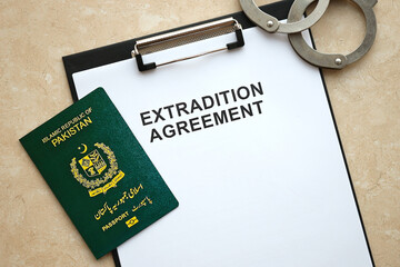 Passport of Pakistan and Extradition Agreement with handcuffs on table close up