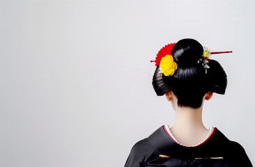 A Japanese woman is having her hair styled into a traditional bun, with flowers and other decorative elements on top. For special occasions, she wears an elegant kimono.