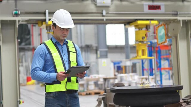 Professional engineer or technician worker hold tablet and walk in workplace area of train factory to check and manage the system.