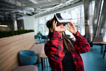 Fototapeta premium Young focused female IT manager using VR glasses in hall of coworking office