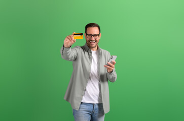Businessman showing credit card and using online shopping apps over smart phone on green background - obrazy, fototapety, plakaty