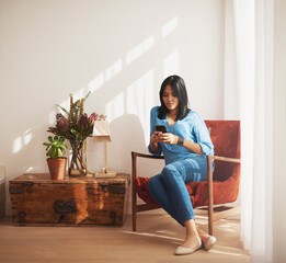 Woman, texting and living room with smartphone on chair for relax with social media with reading in...