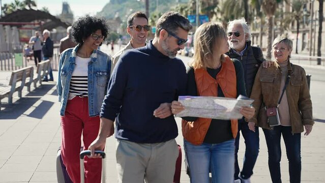 Group of family tourist friends traveling together, walking and checking city map during weekend trip