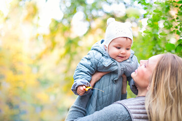 Mother and her little daughter play cuddling on autumn walk in nature outdoors