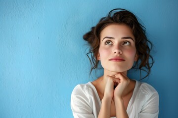 Dreamy Young Woman with Updo Hair Posing Thoughtfully Against Serene Blue Background
