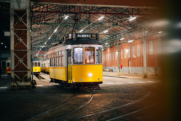 Iconic vintage yellow tram 15 resting in a Lisbon garage at night, symbolizing the city's charm and...