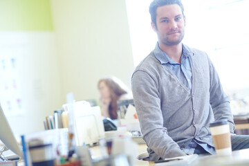 Portrait, man and graphic designer with sitting on desk for creative career, lens flare and startup. Summer, morning and face of teacher in staff room with school, beverage and education for children