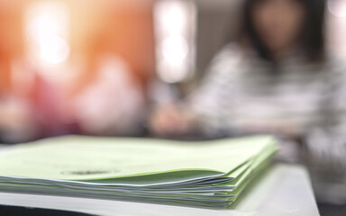 Exam answer sheet pile, blurry application document paperwork stack on office work table in...