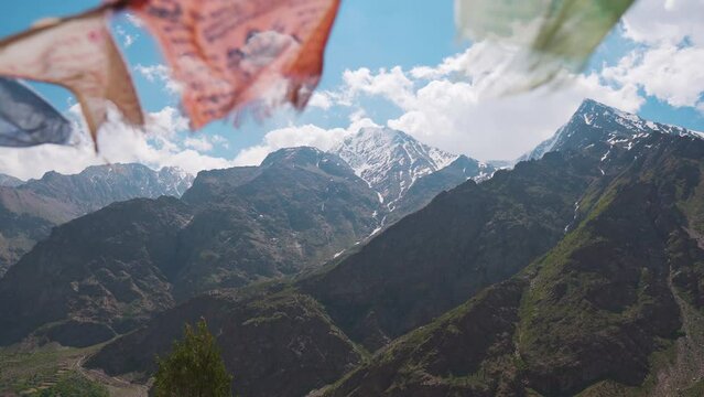 4K shot of colorful Buddhist prayer flags fluttering in wind with Himalaya mountains in background. Mountain peaks, prayer flags and clouds at Chitkul, Himachal Pradesh, India. Nature  landscape.