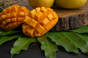 Mango tropical fruit with slice and half cut on green leaf background