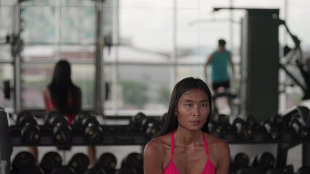 Young asian woman squatting with dumbbell in fitness center, healthy lifestyle
